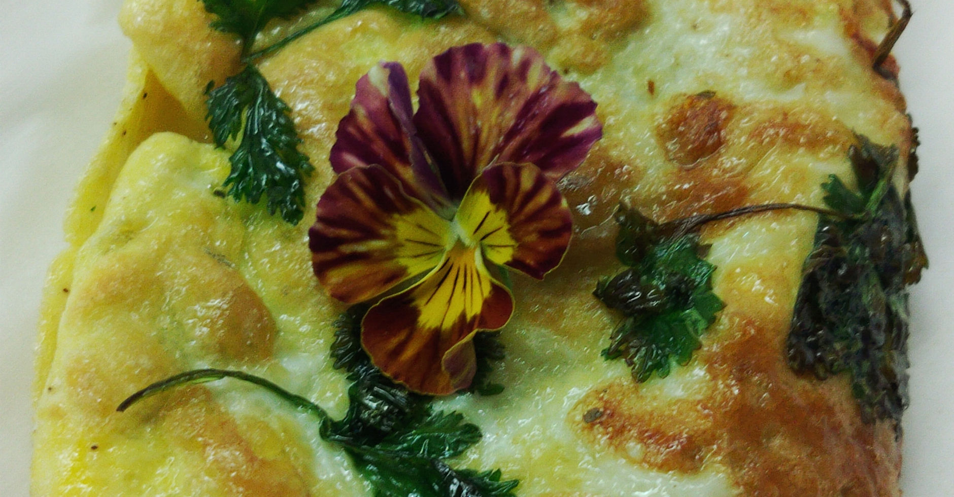 Omelette topped with fried herbs and an edible pansy